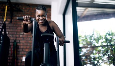 Black woman exercising on elliptical and smiling at home