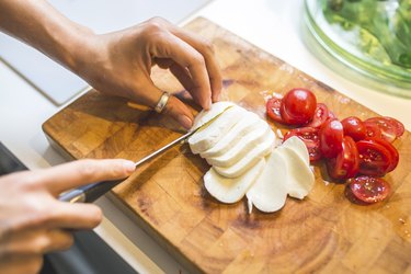 Woman preparing Caprese salad on chopping board