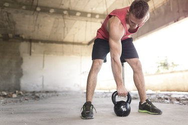 Man doing a dettlebell deadlift to work his hamstrings