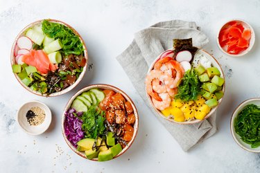 Hawaiian salmon, tuna and shrimp poke bowls with seaweed, avocado, mango, pickled ginger, sesame seeds. Top view, overhead, flat lay