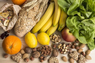 bananas, lettuce, lemons, nuts and other healthy foods on wooden table
