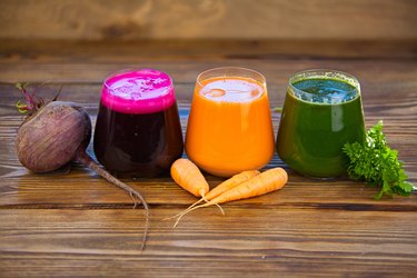 three vegetable juice in glass cup on wooden background