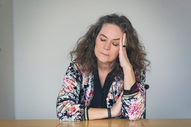 mature woman suffering with eyes closed at table