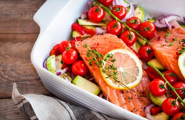 Raw fresh salmon and vegetables in a white casserole dish before cooking as an example of foods to fight inflammation