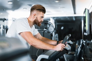Athletic man wearing headphones and working out on a spin bike