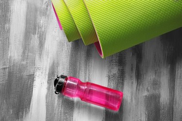 Yoga mat and bottle of water on wooden background for exercise to lower obesity risk