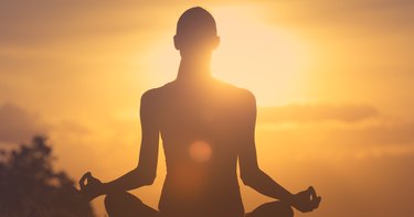 Woman meditating at sunrise