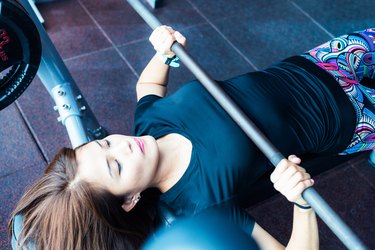 Asian girl lifting weights at the bench press