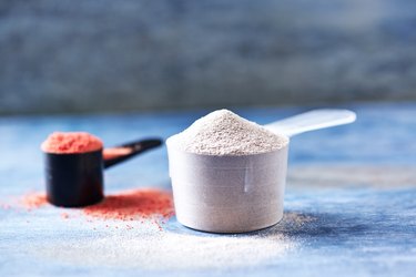 Scoop of Whey Protein and Creatine Powder. Sport nutrition. Rustic wooden background. Close up. Copy space