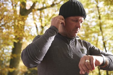 Man On Run Checking Fitness Tracker And Putting In Earphones