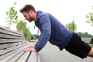 Handsome man doing pushup on bench