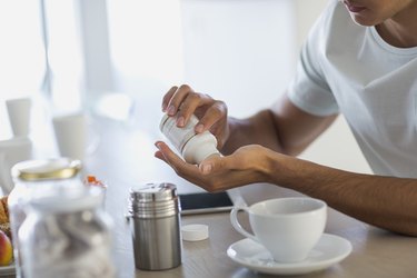 Close-up of a young man taking nutritional supplement pills