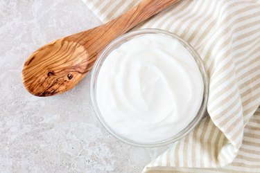 Greek yogurt, with cloth and spoon on white marble