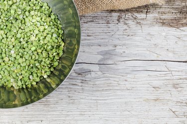 Stainless steel bowl with uncooked green split peas.