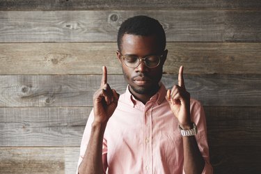 Portrait of handsome young African man, standing against wooden