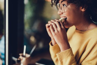 Side view of a woman eating a sandwich in a restaurant