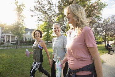 Smiling senior women walking, exercising in sunny park