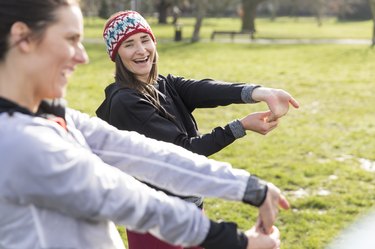 Female runners stretching wrists in park