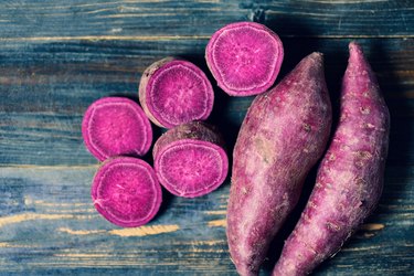 Purple sweet potatoes sliced on a wooden background.