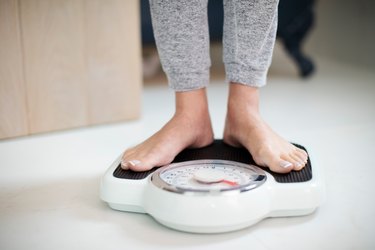 Close up shot of person standing on bathroom scale for nutritarian before and after