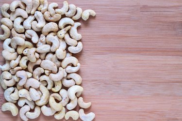 Cashew pile on wooden background. Cashew photo wallpaper. Organic food rustic banner template with text space