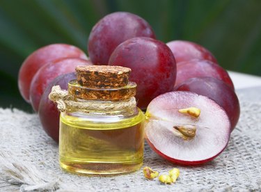 Grape seed oil in a glass jar and fresh grapes on old wooden table in the garden.Spa,bodycare,Bio,Eco products concept.