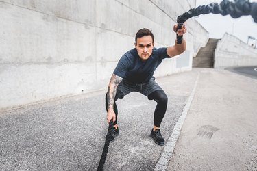 Focused Male Athlete Doing a Workout Finisher with Battle Ropes Outdoors