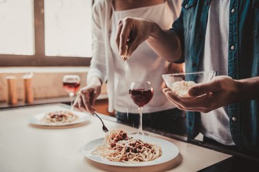 Young couple eating pasta and drinking alcohol, which are some of the foods to avoid with IBS