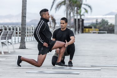 Instructor helping athlete to perform lunges