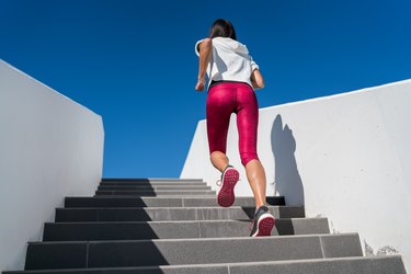 Stairs running woman doing run up on staircase - female runner