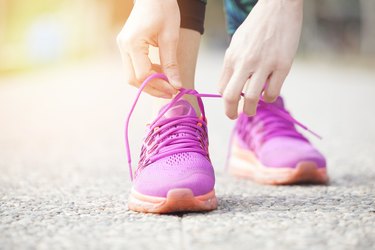 Young woman runner tying pink shoelaces