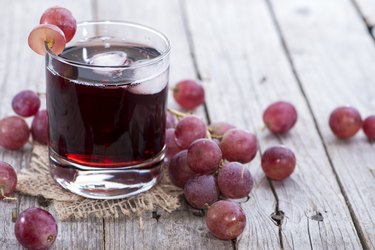 A glass of glucose-rich red grape juice on gray wood