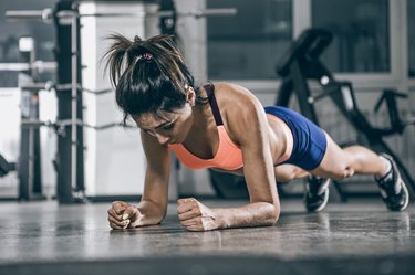 Muscular woman on a plank position.