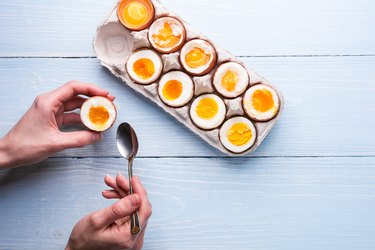 boiled eggs in hands on a wooden background, as an example of what to eat when you're hungry and trying to lose weight