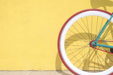 Close-up of bicycle parked by yellow wall with red tire