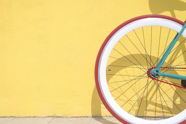 Close-Up Of Bicycle Parked By Yellow Wall with Red Tire