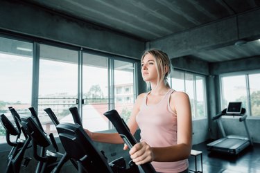 Portrait of Pretty Asian Woman is Workout in Fitness Gym., Attractive Woman is Working Out on Elliptical Machine Machine., Sport Club and Healthy Concept.