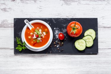 Gazpacho. Traditional Spanish tomato soup with fresh tomatoes, fresh cucumber, on white wood base. Top view