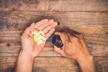 bottle pouring pills on a male’s hand