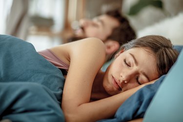 Woman sleeping with her husband in bed