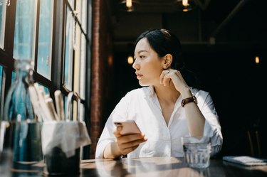 年轻女人享受温暖的阳光和有一个放松的时间在咖啡馆