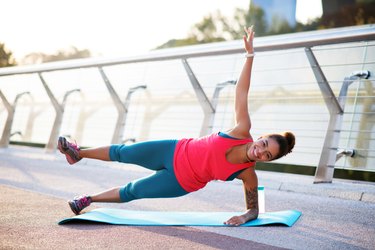 Woman raising her leg while doing side plank