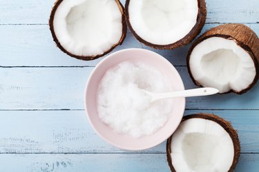 Coconuts fruit with coconut oil on blue wooden table top view. Beauty and spa organic cosmetic.