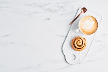 Freshly baked cinnamon roll and coffee with latte art