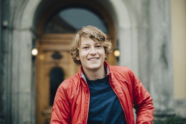 Portrait of smiling teenager against building in city