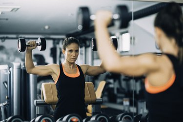 Young woman exercising in front of the mirror