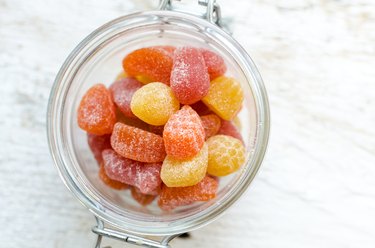 Yellow, orange and red gummy vitamins in a glass jar.