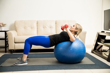 Woman lifting weights and using stability ball