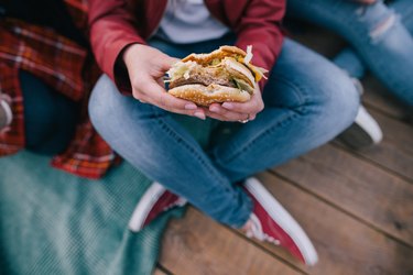 Tasty burger in woman's hands. Takeaway junk food