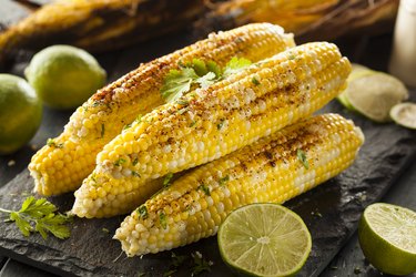 Grilled Mexican-inspired corn on the cob with cut limes